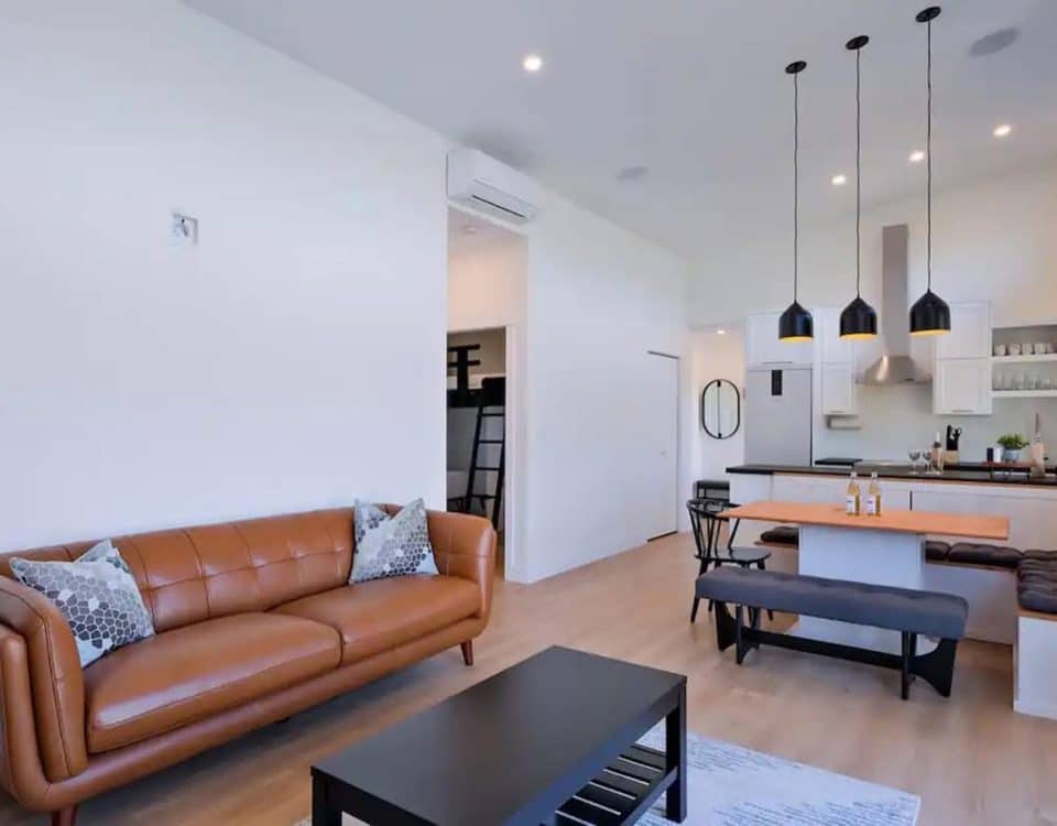 A cozy living room featuring a comfortable couch, a coffee table, and an open kitchen area in the background.