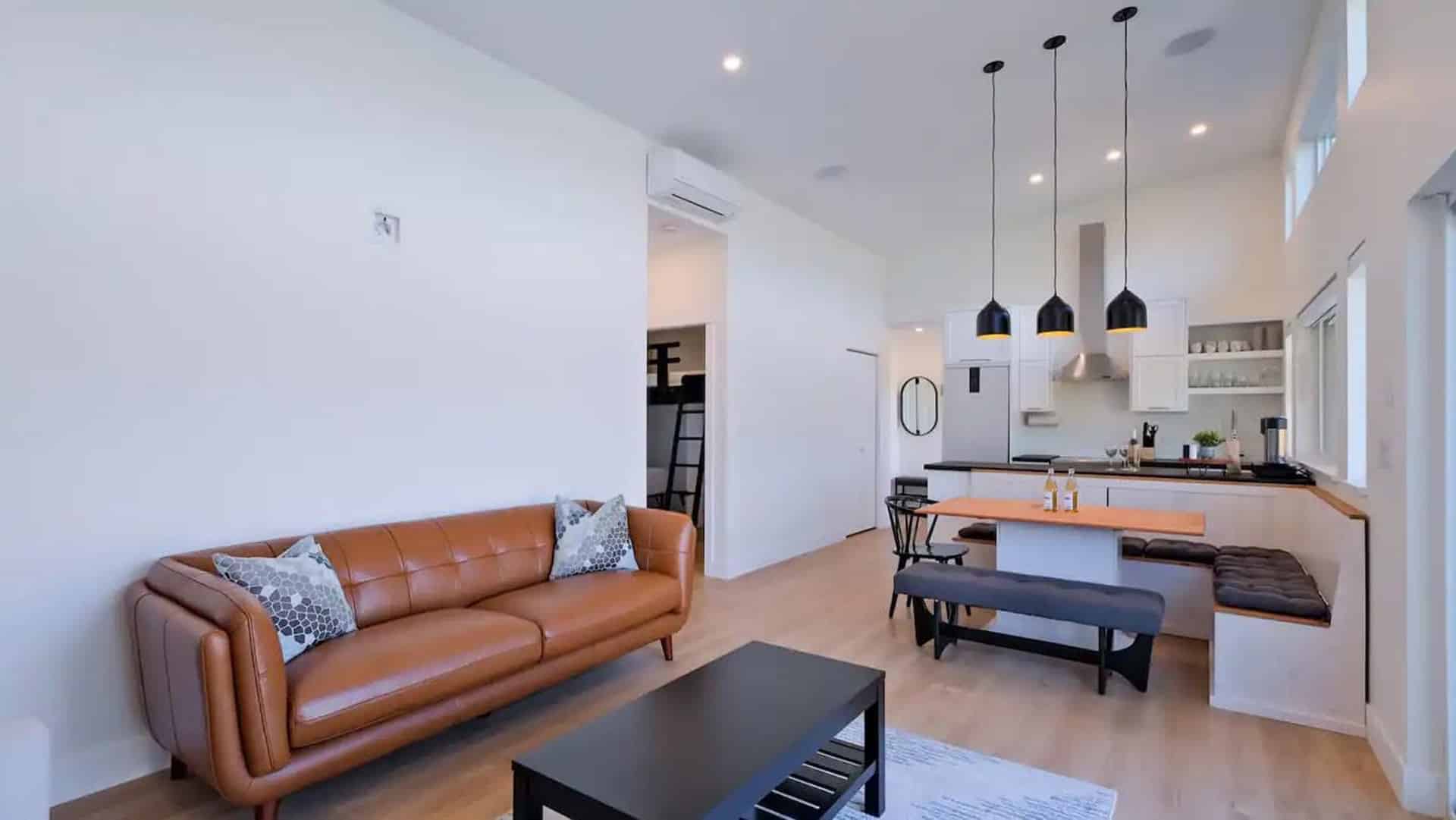 A cozy living room featuring a comfortable couch, a coffee table, and an open kitchen area in the background.