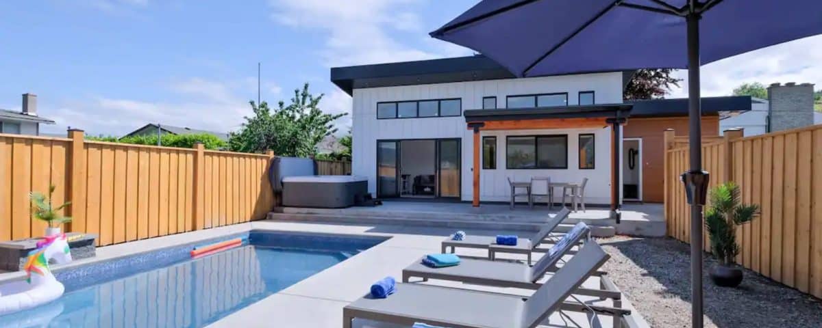A backyard featuring a swimming pool surrounded by patio furniture, creating a relaxing outdoor space.