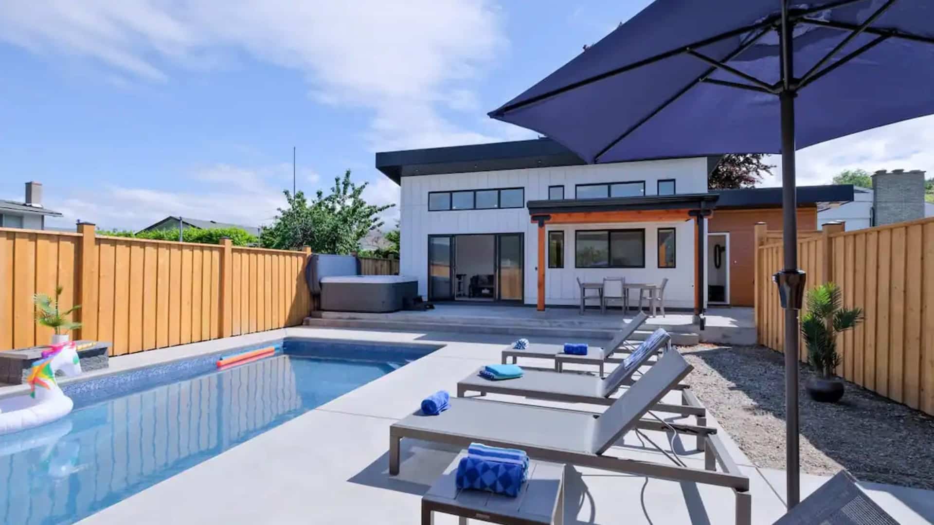 A backyard featuring a swimming pool surrounded by patio furniture, creating a relaxing outdoor space.