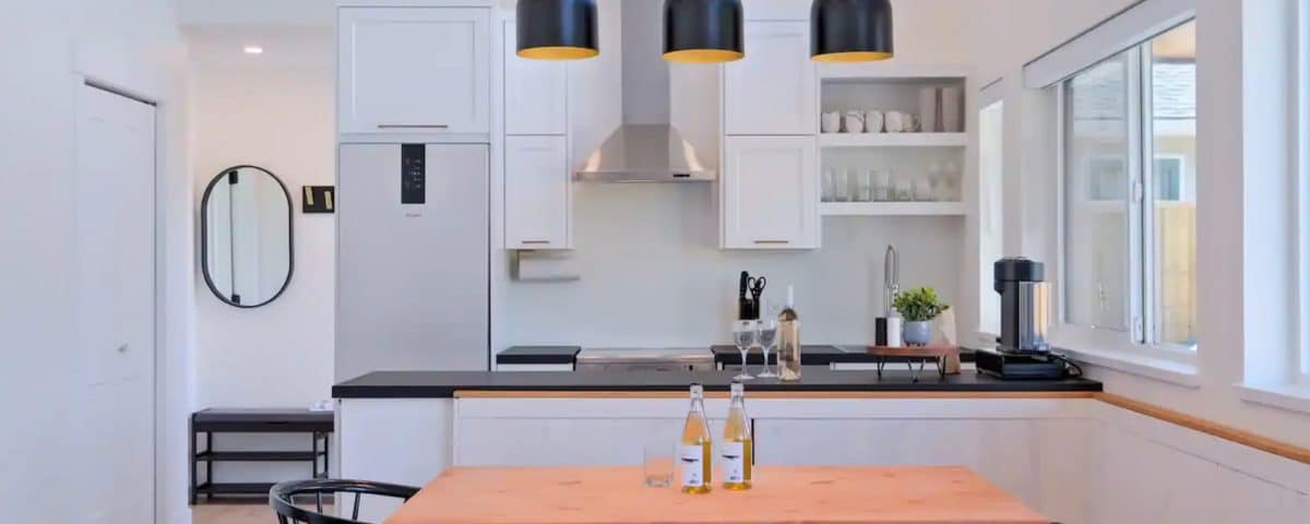 A kitchen featuring a wooden table surrounded by four chairs, with cabinets and appliances in the background.