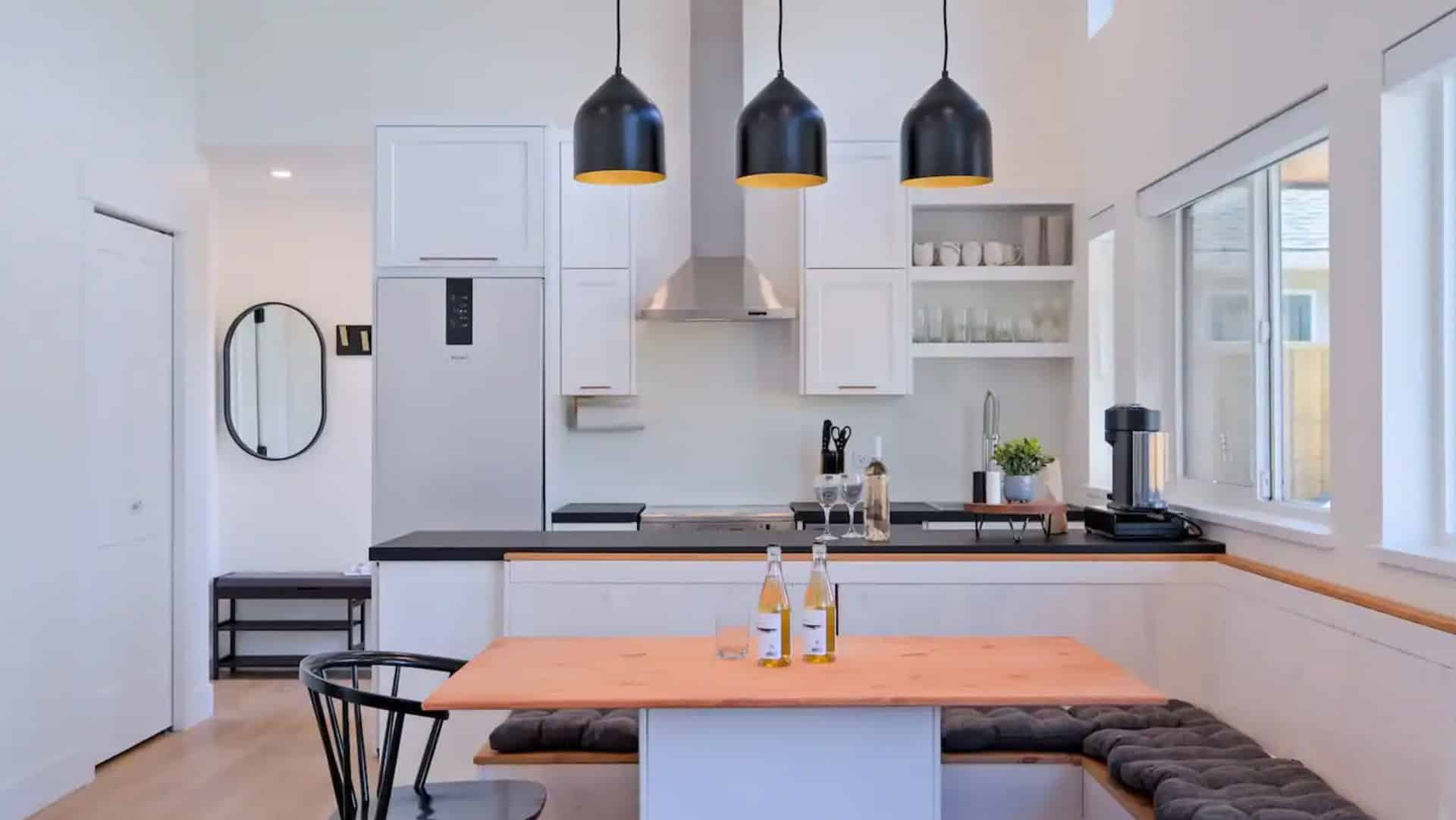 A kitchen featuring a wooden table surrounded by four chairs, with cabinets and appliances in the background.