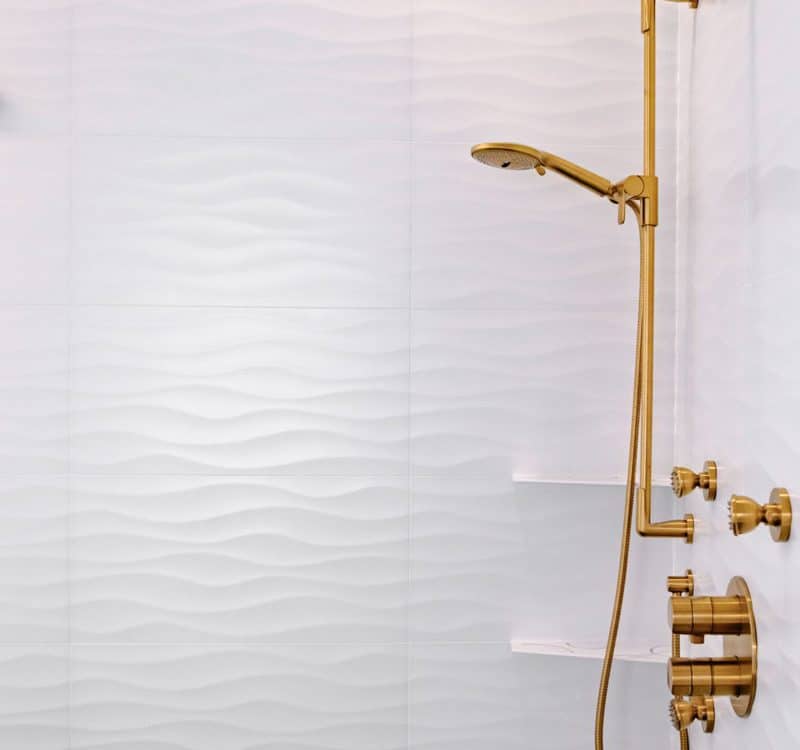 A sleek modern bathroom featuring a stylish gold shower head against a minimalist backdrop.