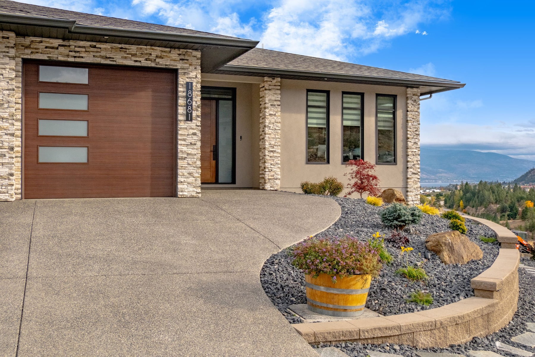 A house featuring a driveway leading to a garage, surrounded by a well-maintained lawn and landscaping.