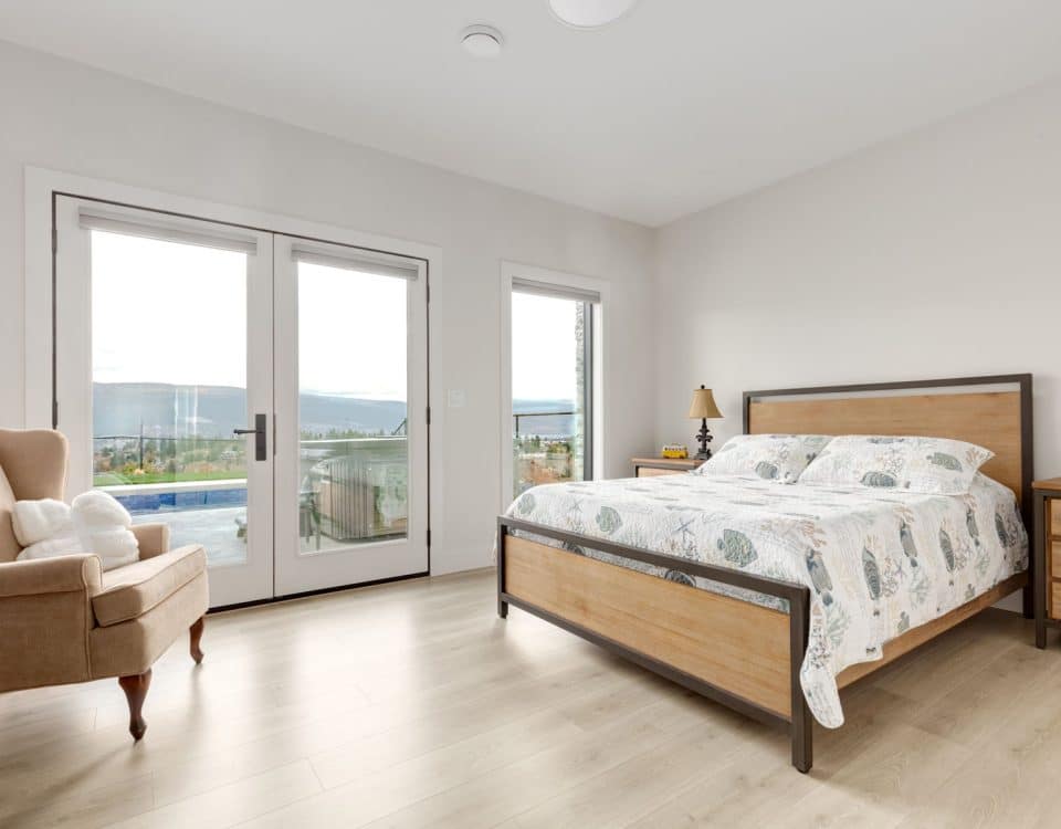 A cozy bedroom featuring a bed, a dresser, and sliding glass doors that open to a view outside.