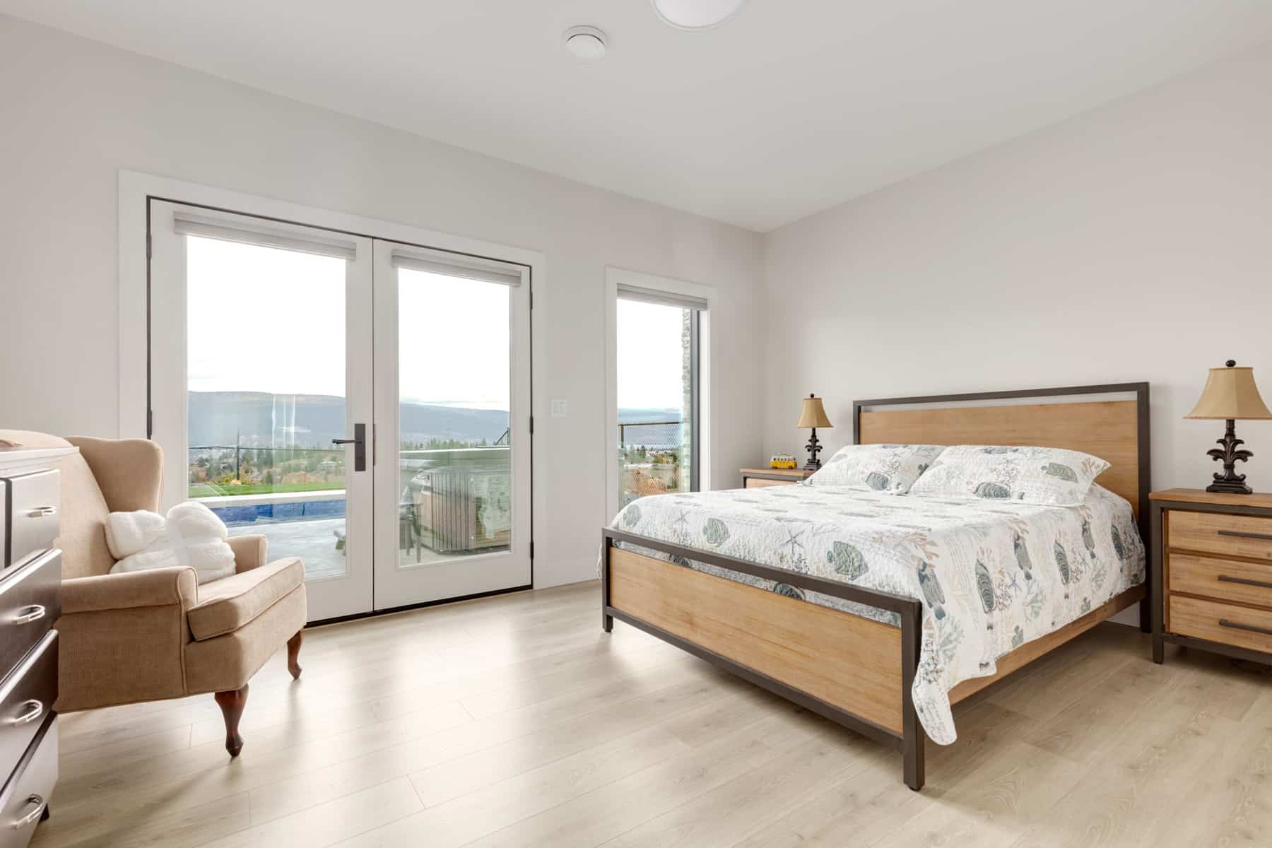 A cozy bedroom featuring a bed, a dresser, and sliding glass doors that open to a view outside.