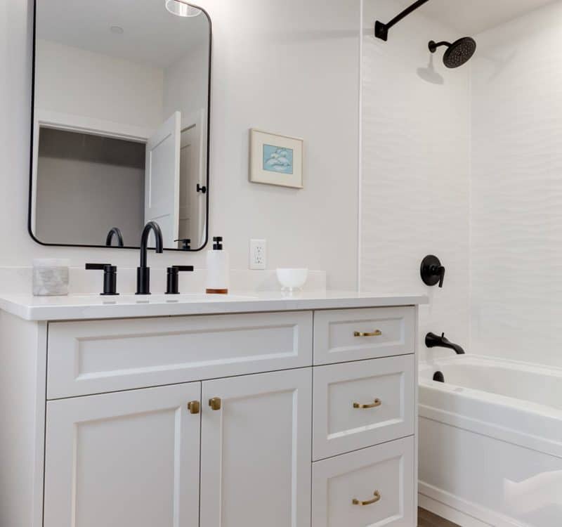 A modern bathroom featuring white cabinets and a spacious bathtub, creating a clean and inviting atmosphere.