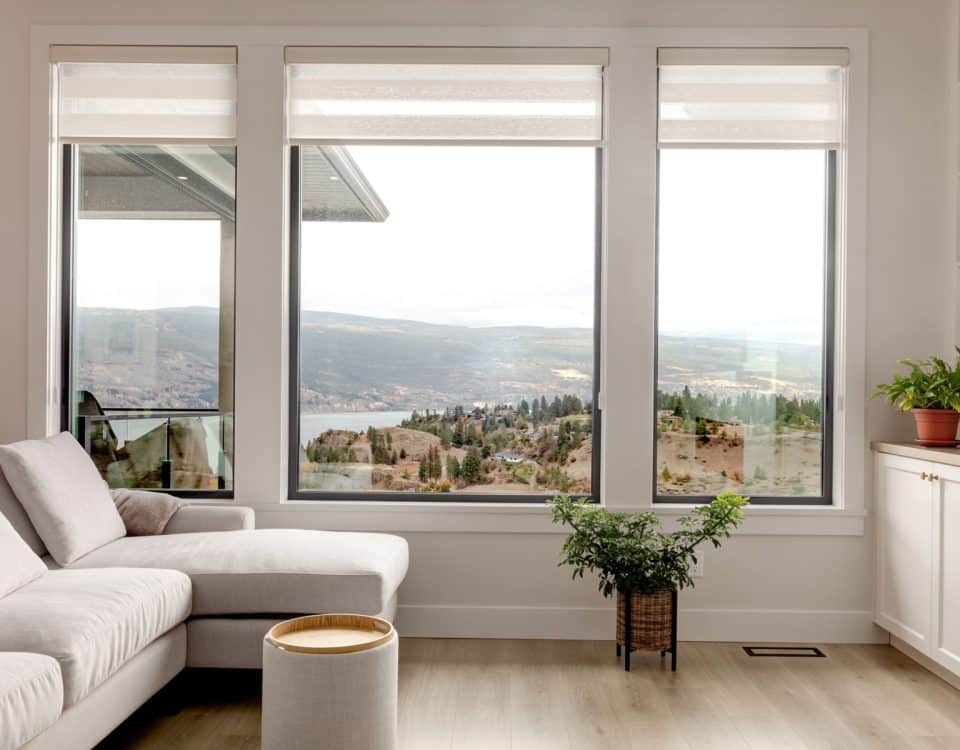 A cozy living room featuring a couch and large windows that provide a view of the serene lake outside.