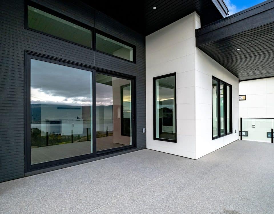 A modern home featuring large windows and a spacious balcony, showcasing contemporary architectural design.