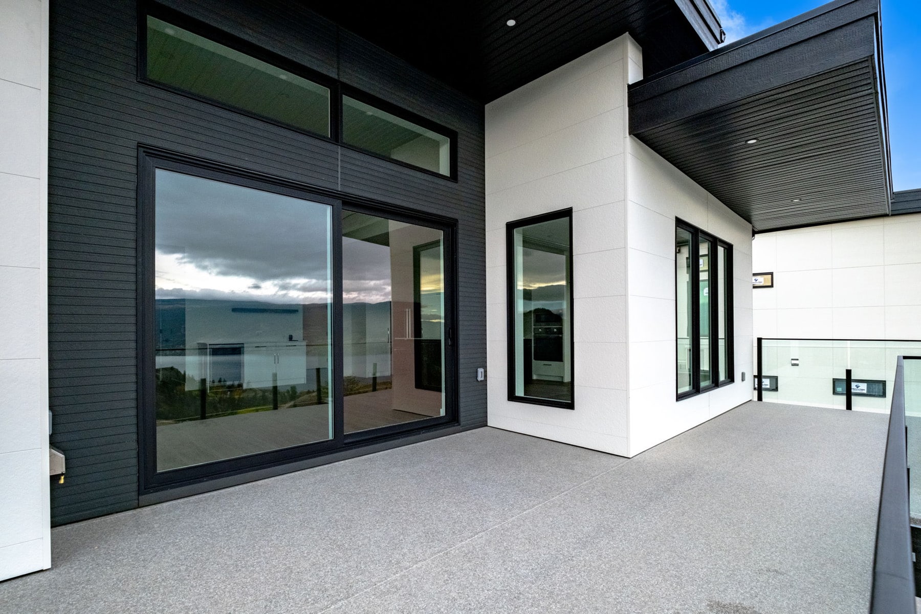 A modern home featuring large windows and a spacious balcony, showcasing contemporary architectural design.