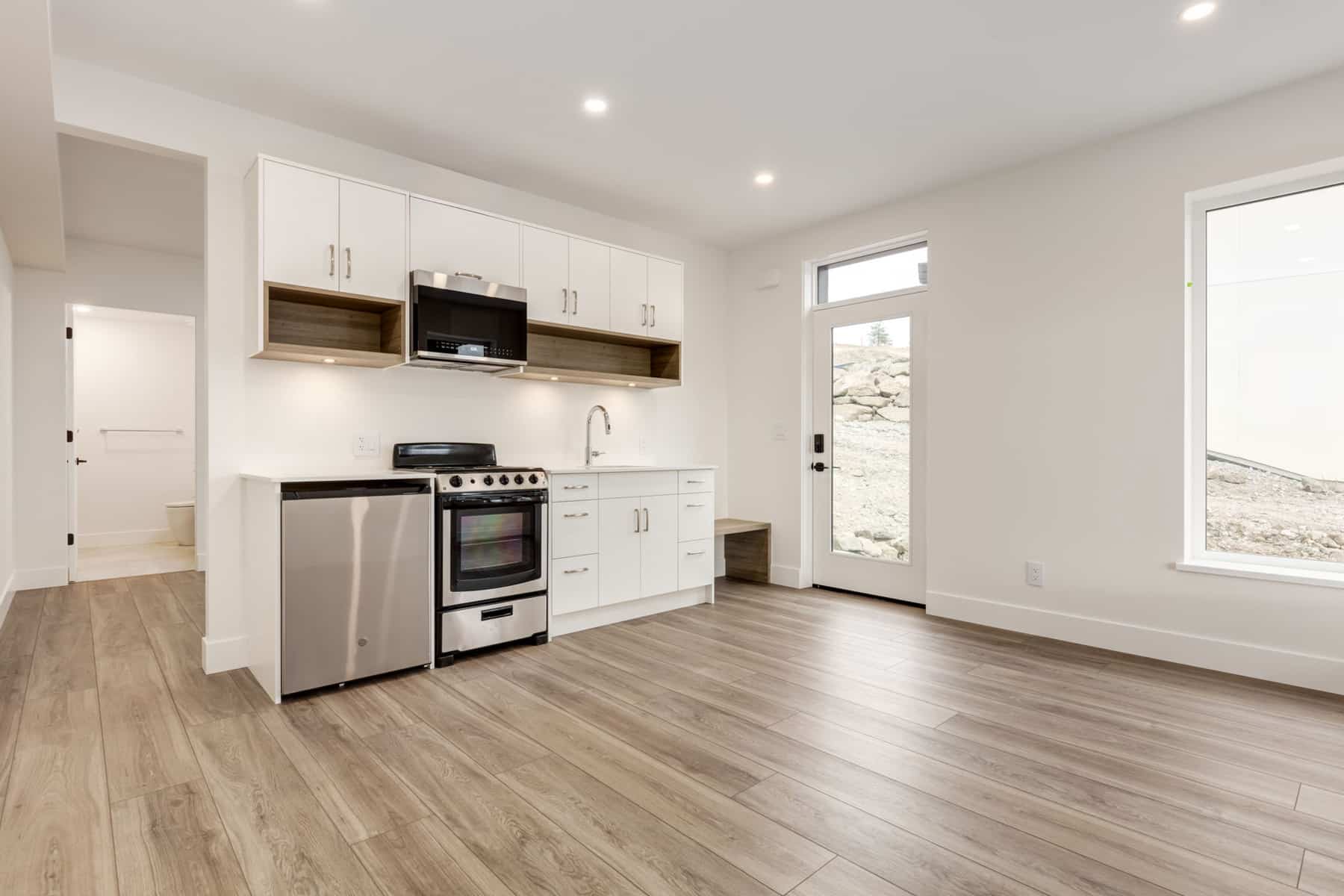A clean kitchen featuring white cabinets and warm wood floors, creating a bright and inviting atmosphere.