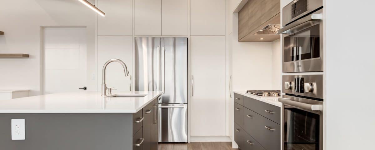 A modern kitchen featuring stainless steel appliances and elegant wood flooring.