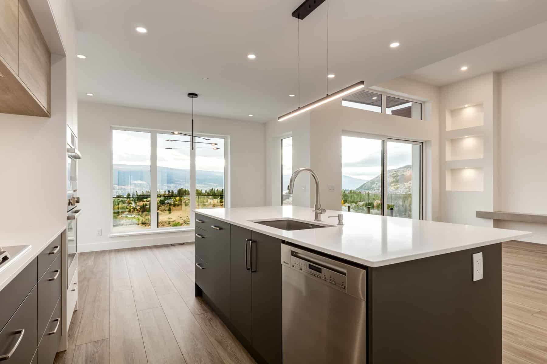A modern kitchen featuring stainless steel appliances and a scenic view of the mountains through a large window.