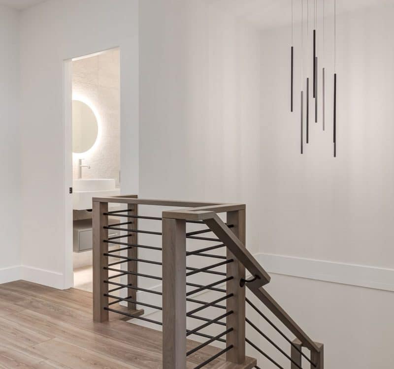 A modern home interior featuring a stylish staircase and an elegant chandelier hanging from the ceiling.
