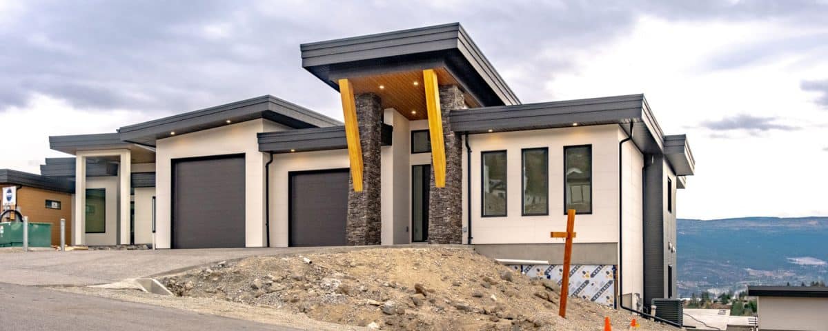 A modern home featuring a garage, set against a backdrop of scenic mountains.
