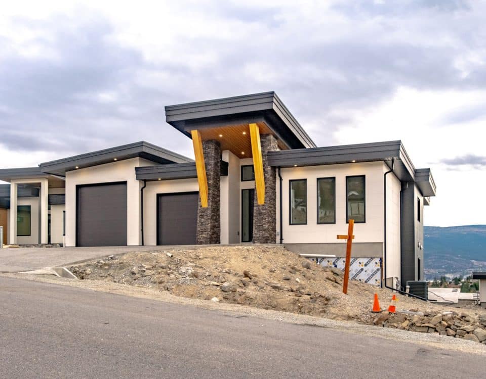 A modern home featuring a garage, set against a backdrop of scenic mountains.