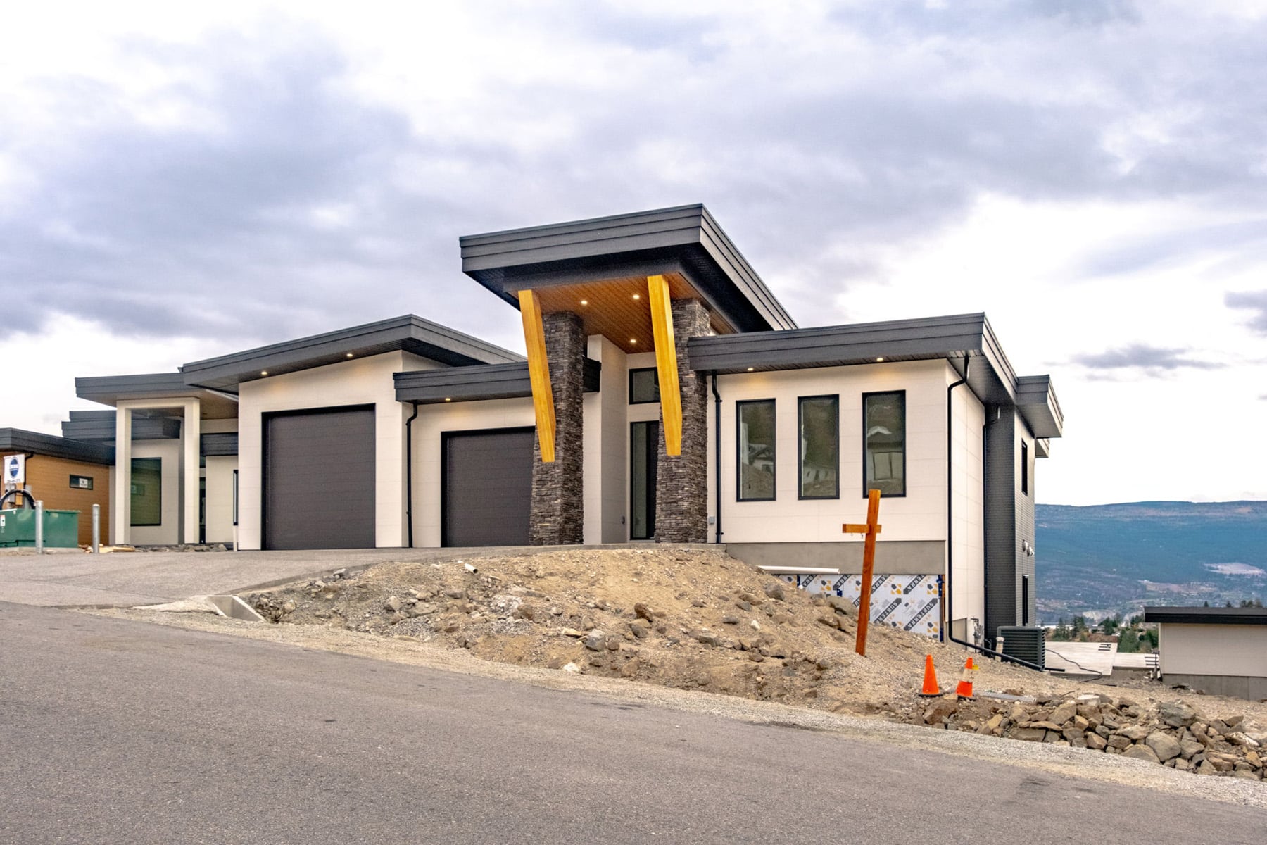 A modern home featuring a garage, set against a backdrop of scenic mountains.