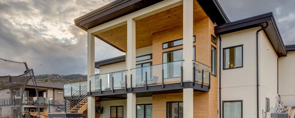 A modern home featuring a spacious deck and a large yard, showcasing contemporary architecture and outdoor living space.