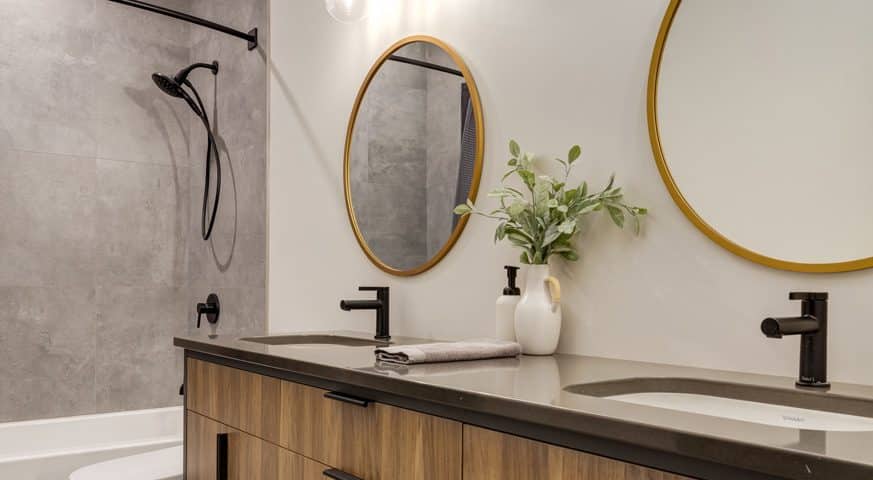 A modern bathroom featuring a large mirror above wooden cabinets, showcasing a sleek and stylish design.