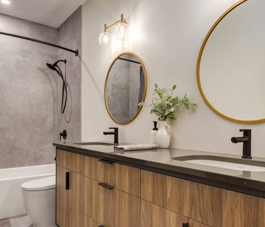 A modern bathroom featuring a large mirror above wooden cabinets, showcasing a sleek and stylish design.