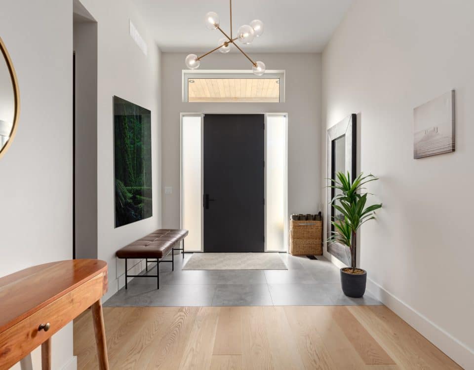 A hallway featuring a polished wooden floor and a large mirror reflecting the space.