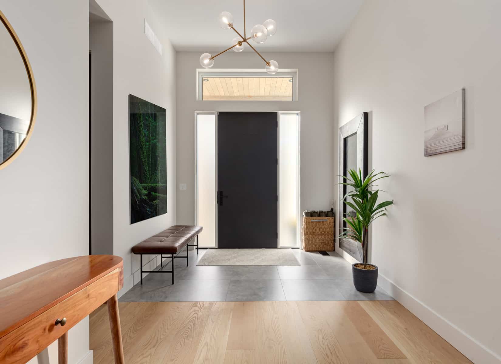 A hallway featuring a polished wooden floor and a large mirror reflecting the space.
