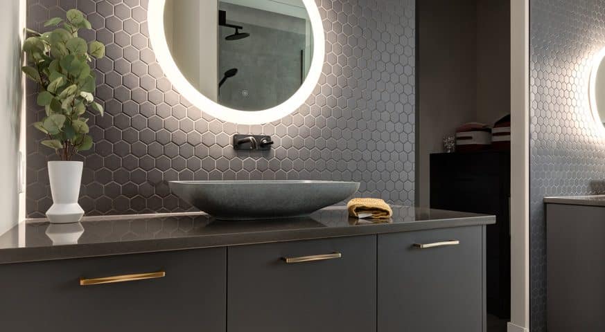 A modern bathroom featuring a large mirror above a sleek sink, showcasing contemporary design elements and clean lines.