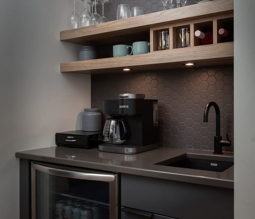A modern kitchen featuring a sink, refrigerator, and coffee maker, showcasing a clean and organized space.