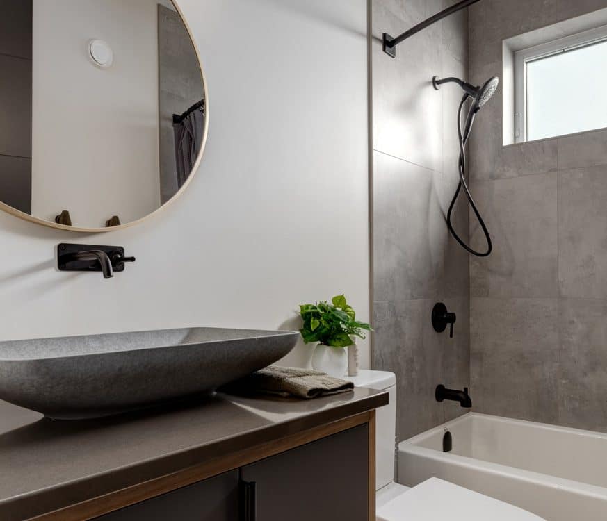 A modern bathroom featuring a round mirror above a sleek sink, showcasing contemporary design elements and clean lines.