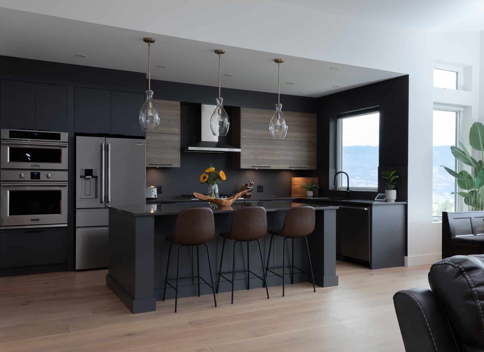 A modern kitchen featuring dark wood floors and sleek black cabinets, creating a stylish and contemporary atmosphere.