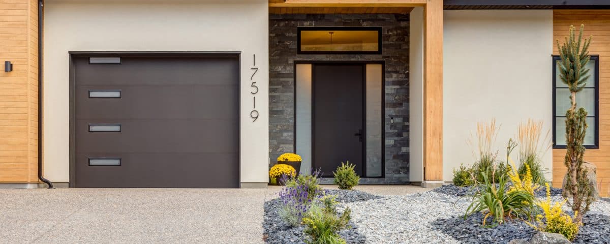 Modern home featuring a garage, surrounded by well-maintained landscaping and a clear blue sky in the background.