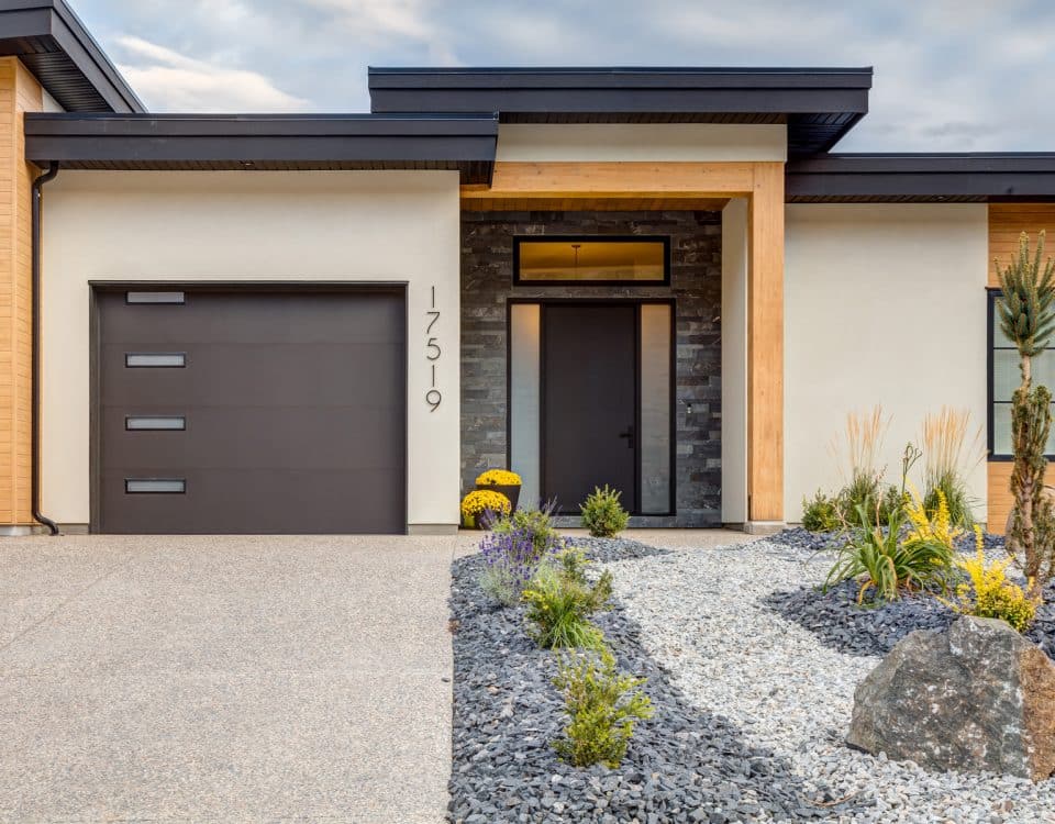 Modern home featuring a garage, surrounded by well-maintained landscaping and a clear blue sky in the background.