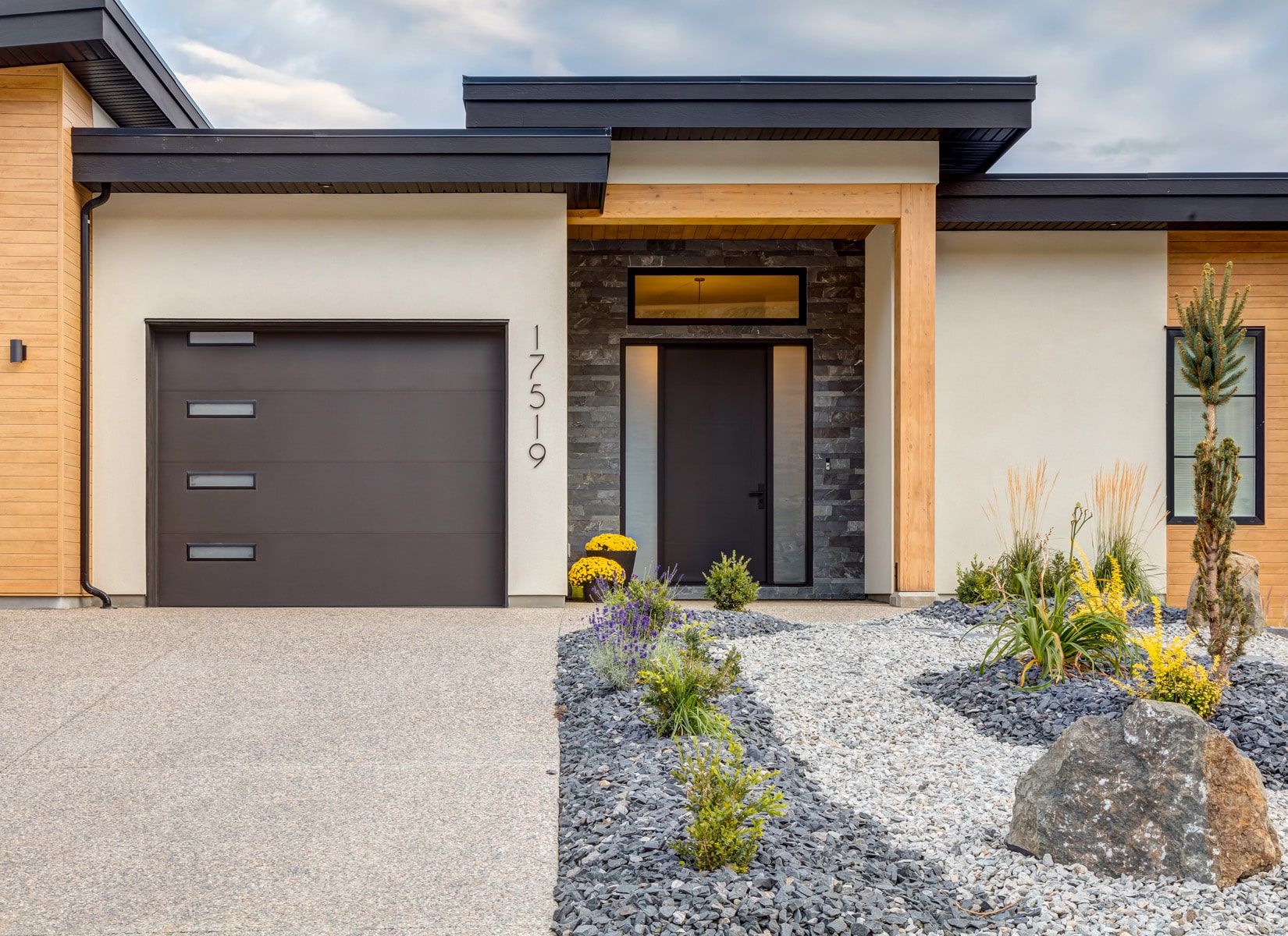 Modern home featuring a garage, surrounded by well-maintained landscaping and a clear blue sky in the background.