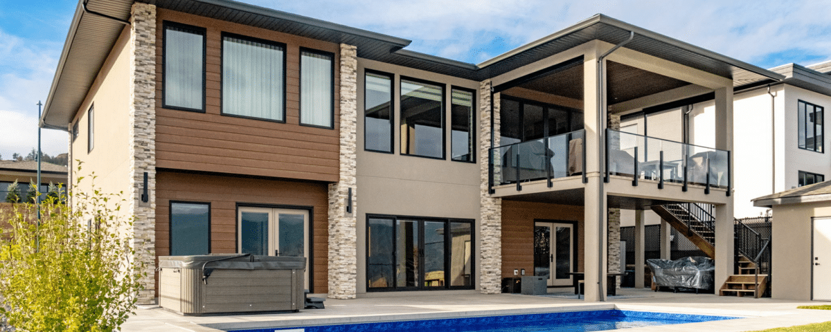 A contemporary home featuring a swimming pool and a spacious patio area, surrounded by lush greenery.