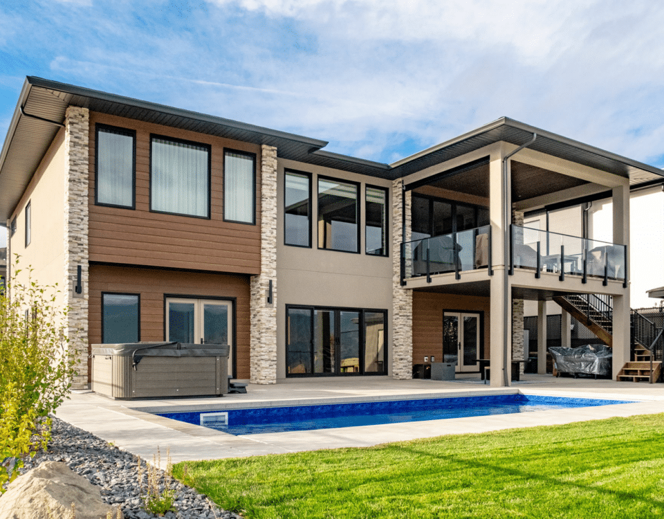 A contemporary home featuring a swimming pool and a spacious patio area, surrounded by lush greenery.