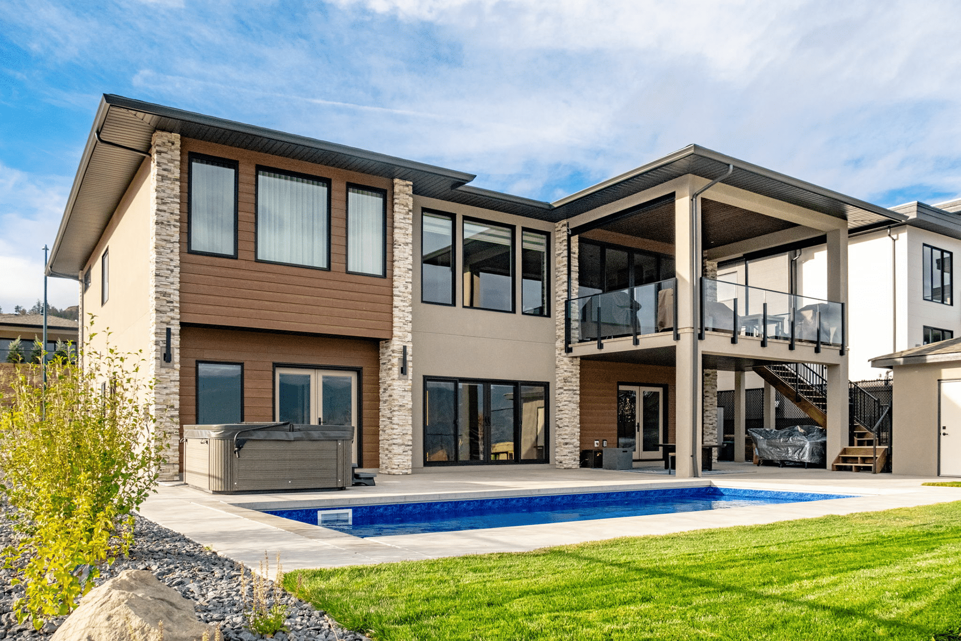 A contemporary home featuring a swimming pool and a spacious patio area, surrounded by lush greenery.