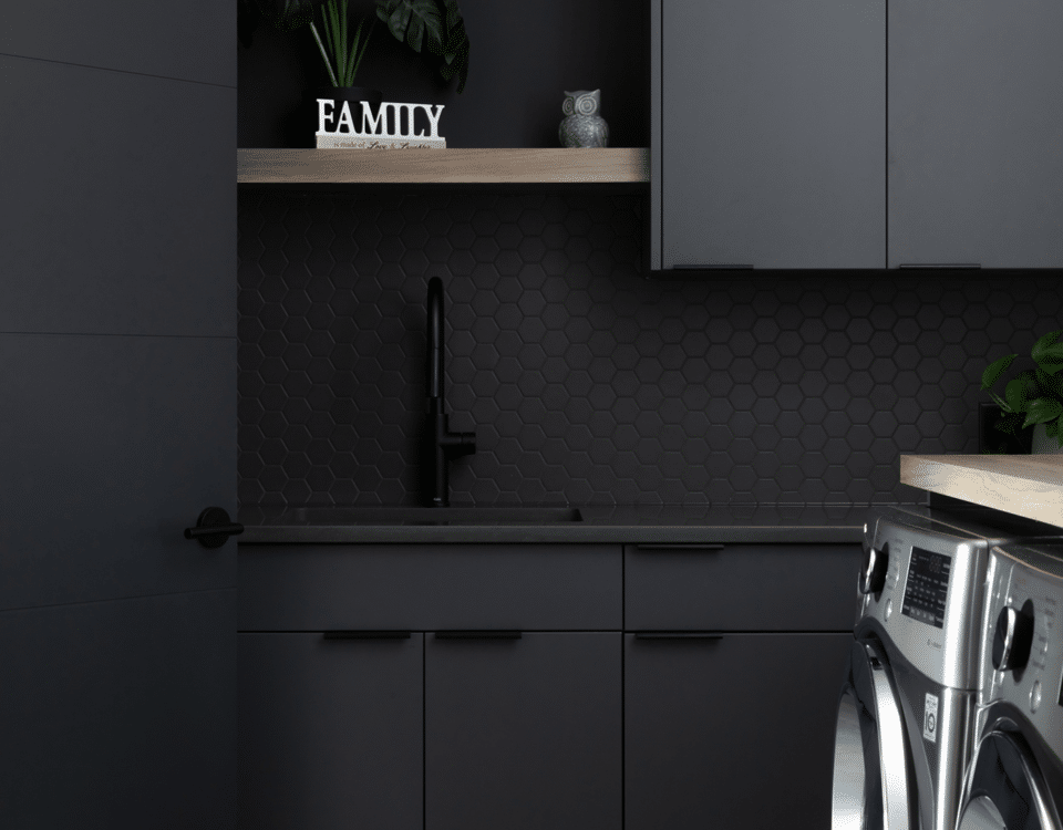 A modern laundry room featuring sleek black cabinets and a washing machine, showcasing a stylish and functional design.