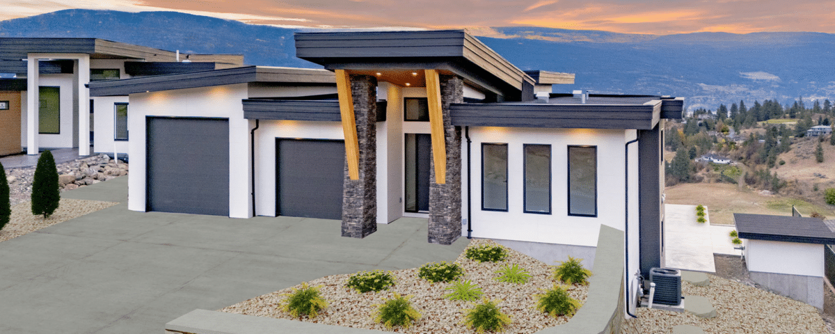 A house with a driveway and garage silhouetted against a vibrant sunset sky.