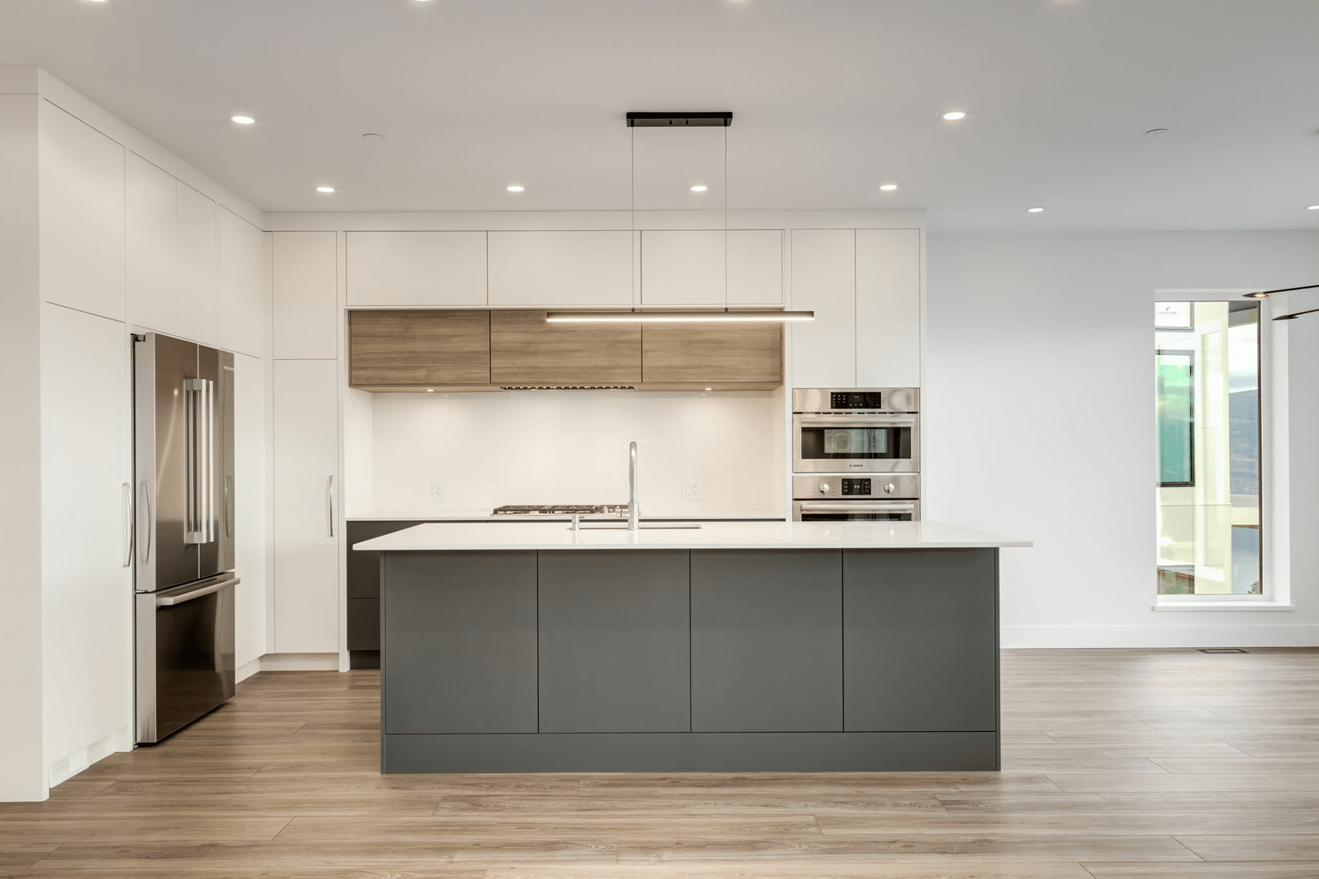 A modern kitchen featuring sleek white cabinets and warm wooden floors, creating a bright and inviting atmosphere.