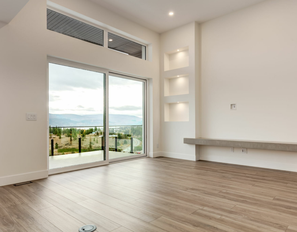A spacious empty room featuring hardwood floors and large sliding glass doors allowing natural light to enter.