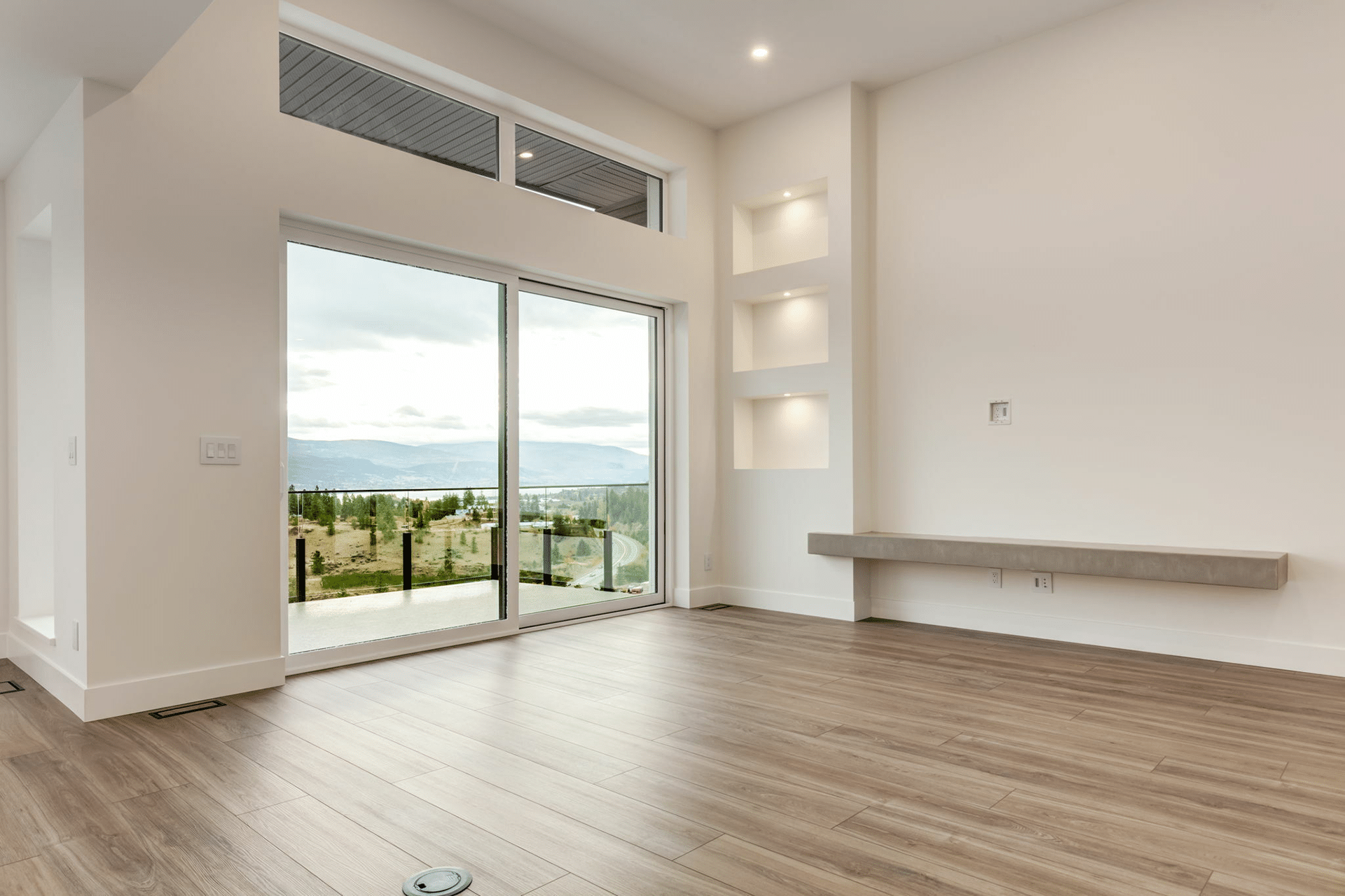 A spacious empty room featuring hardwood floors and large sliding glass doors allowing natural light to enter.