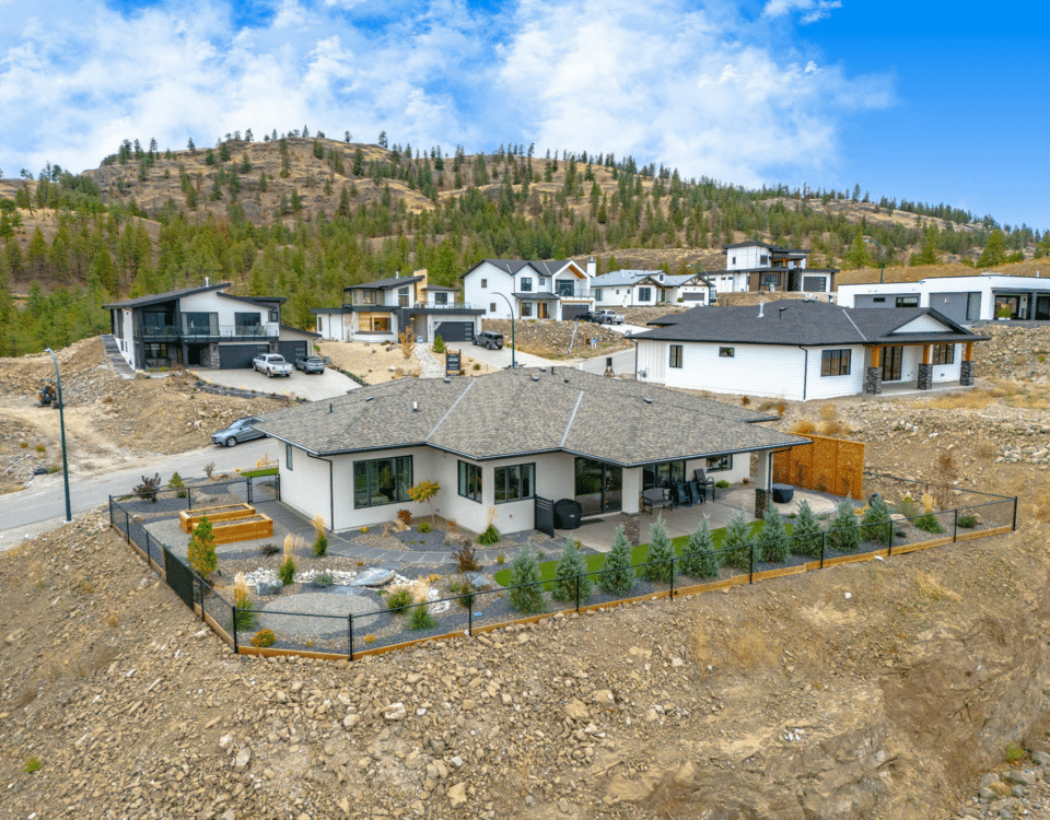 A house perched on a hillside, overlooking a scenic view of distant mountains under a clear blue sky.