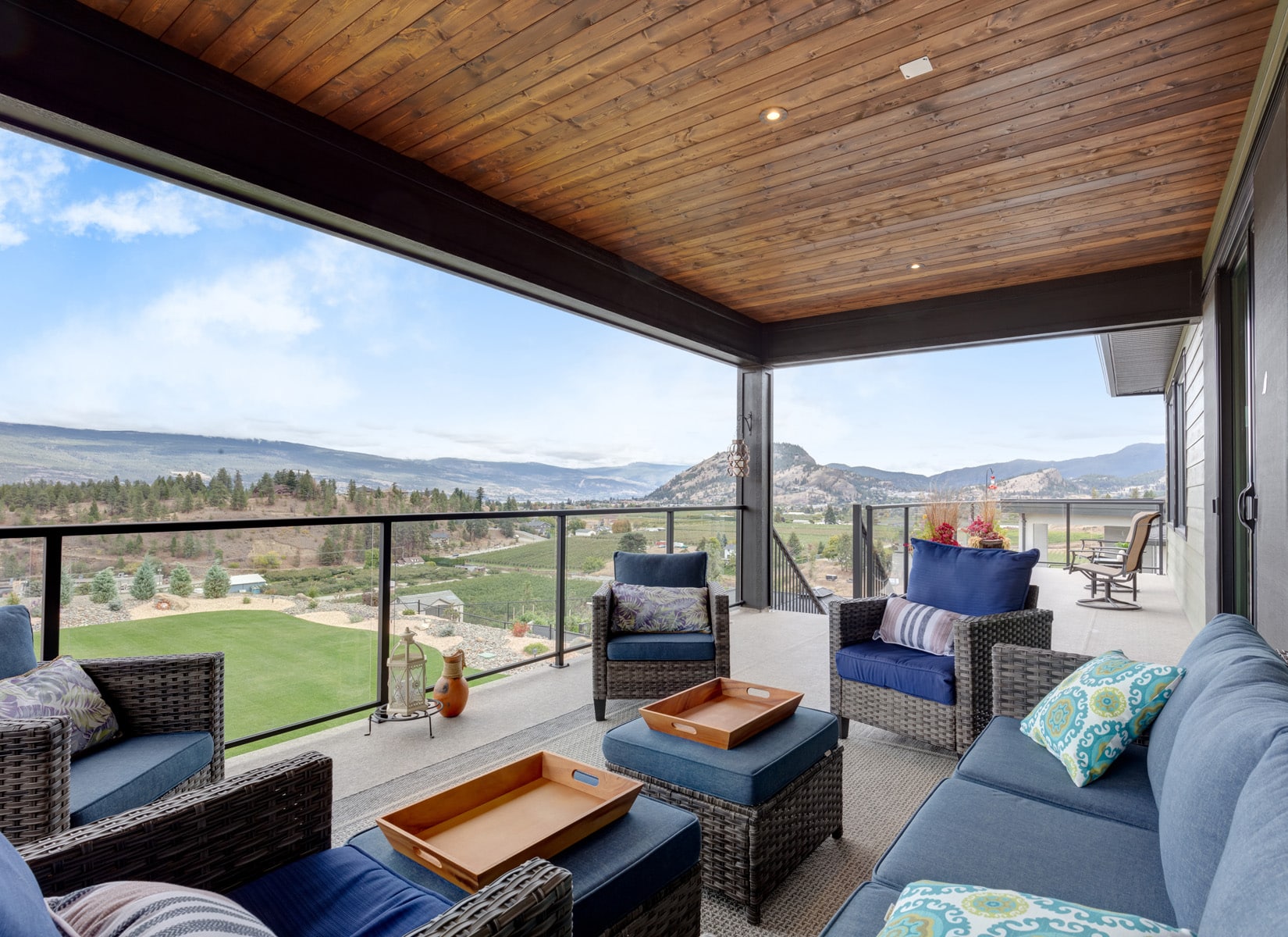 A patio featuring wicker furniture overlooks a scenic view of the mountains in the background.