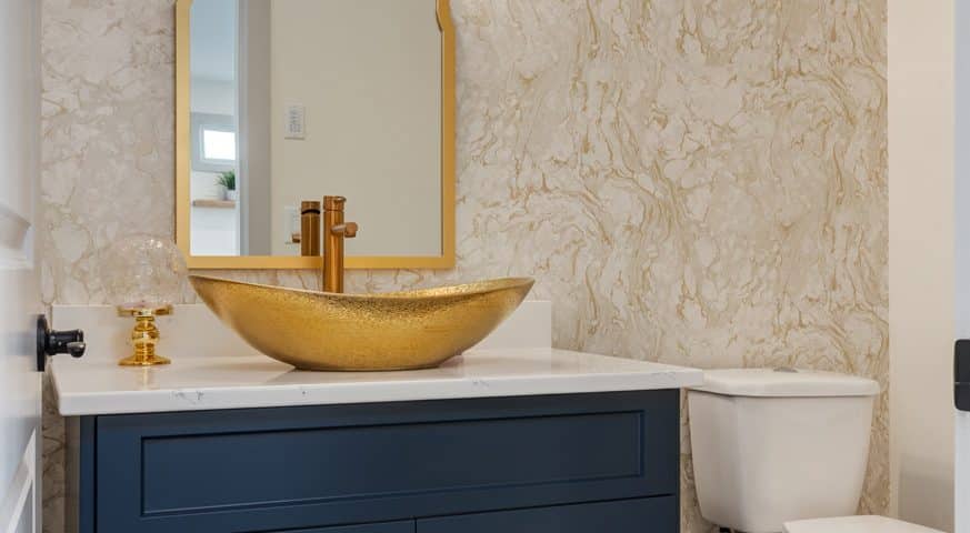 A stylish bathroom featuring elegant gold fixtures and modern blue cabinets, creating a luxurious and contemporary atmosphere