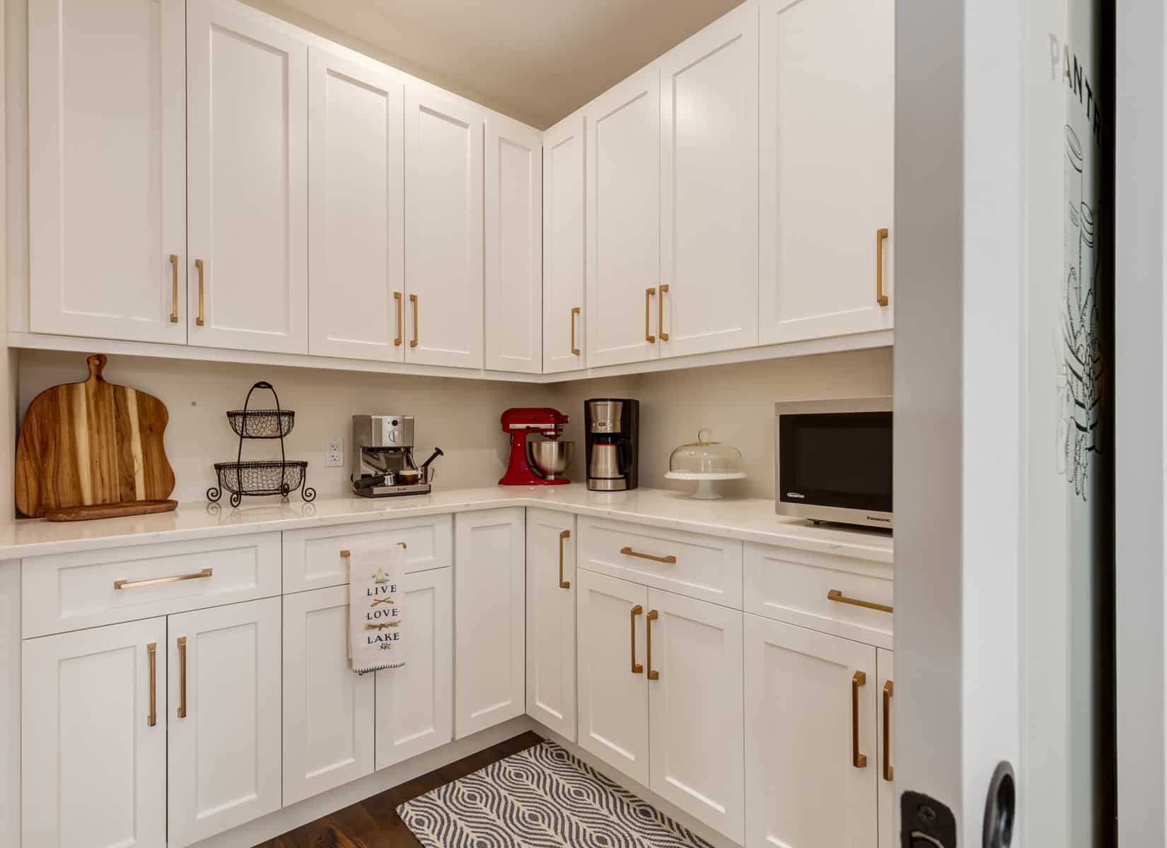 A modern kitchen featuring white cabinets and a sleek coffee maker on the countertop.