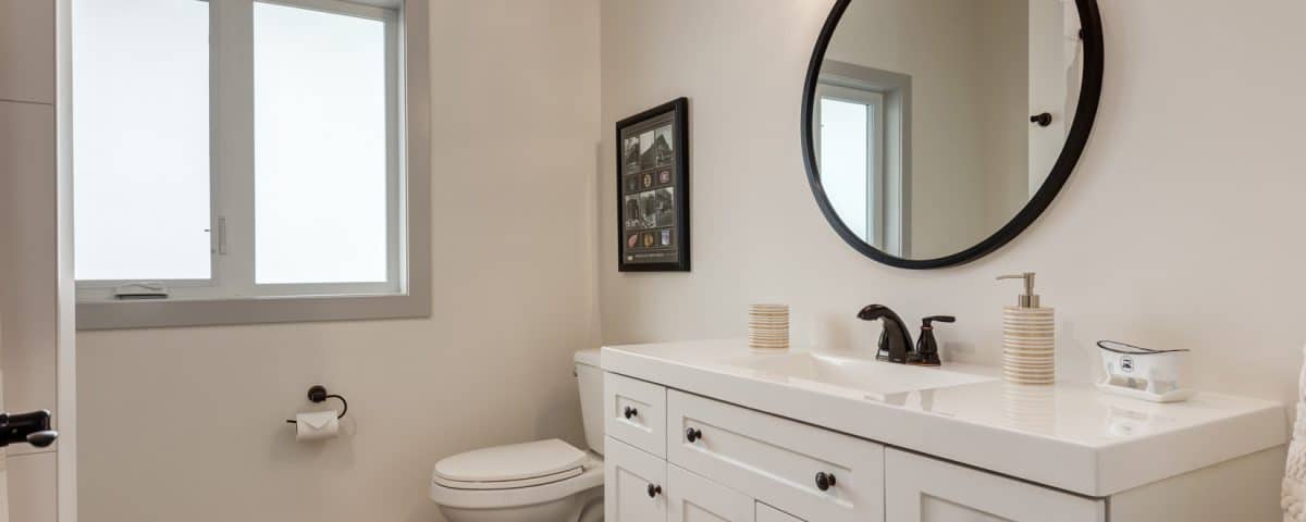 A modern bathroom featuring a white vanity and a sleek black toilet against a neutral wall.