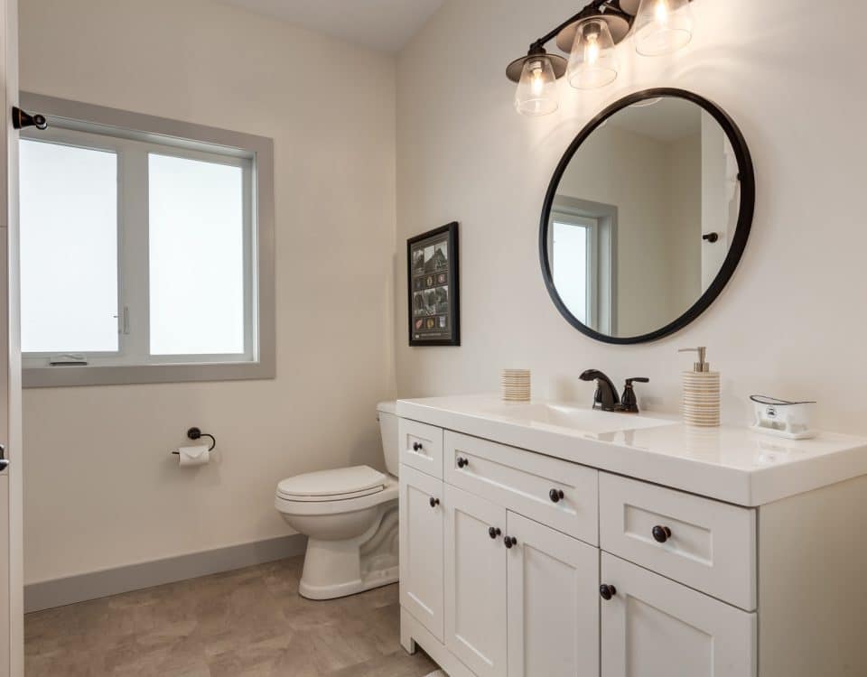 A modern bathroom featuring a white vanity and a sleek black toilet against a neutral wall.