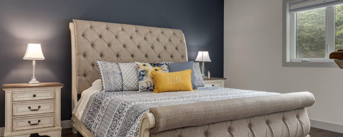 A cozy bedroom featuring blue walls and a neatly made white bed, creating a calm and inviting atmosphere.