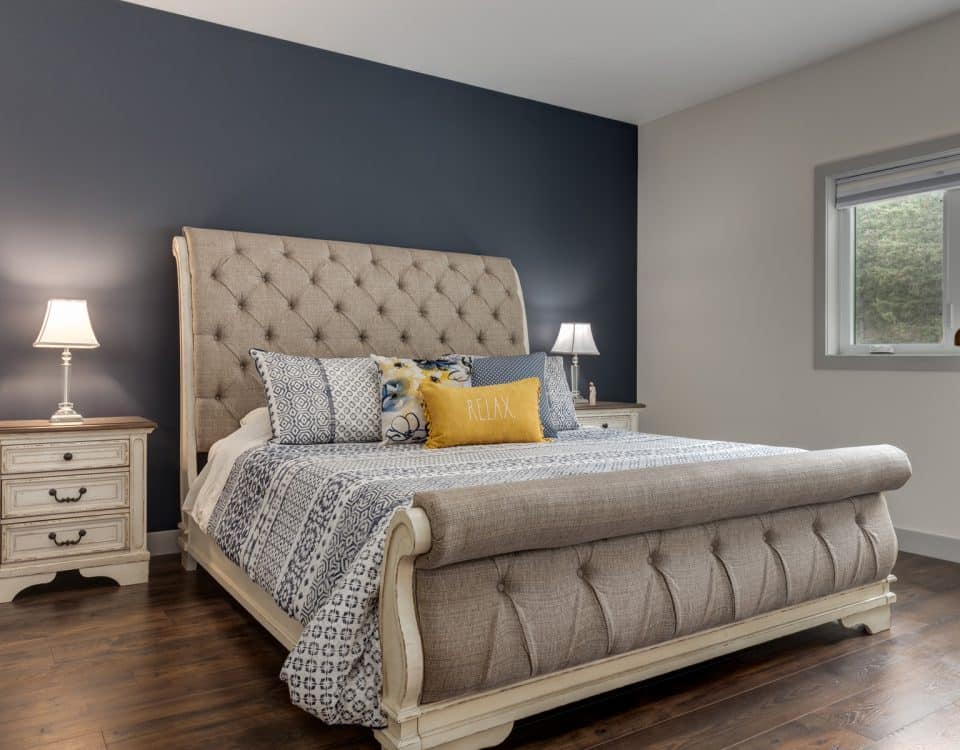A cozy bedroom featuring blue walls and a neatly made white bed, creating a calm and inviting atmosphere.