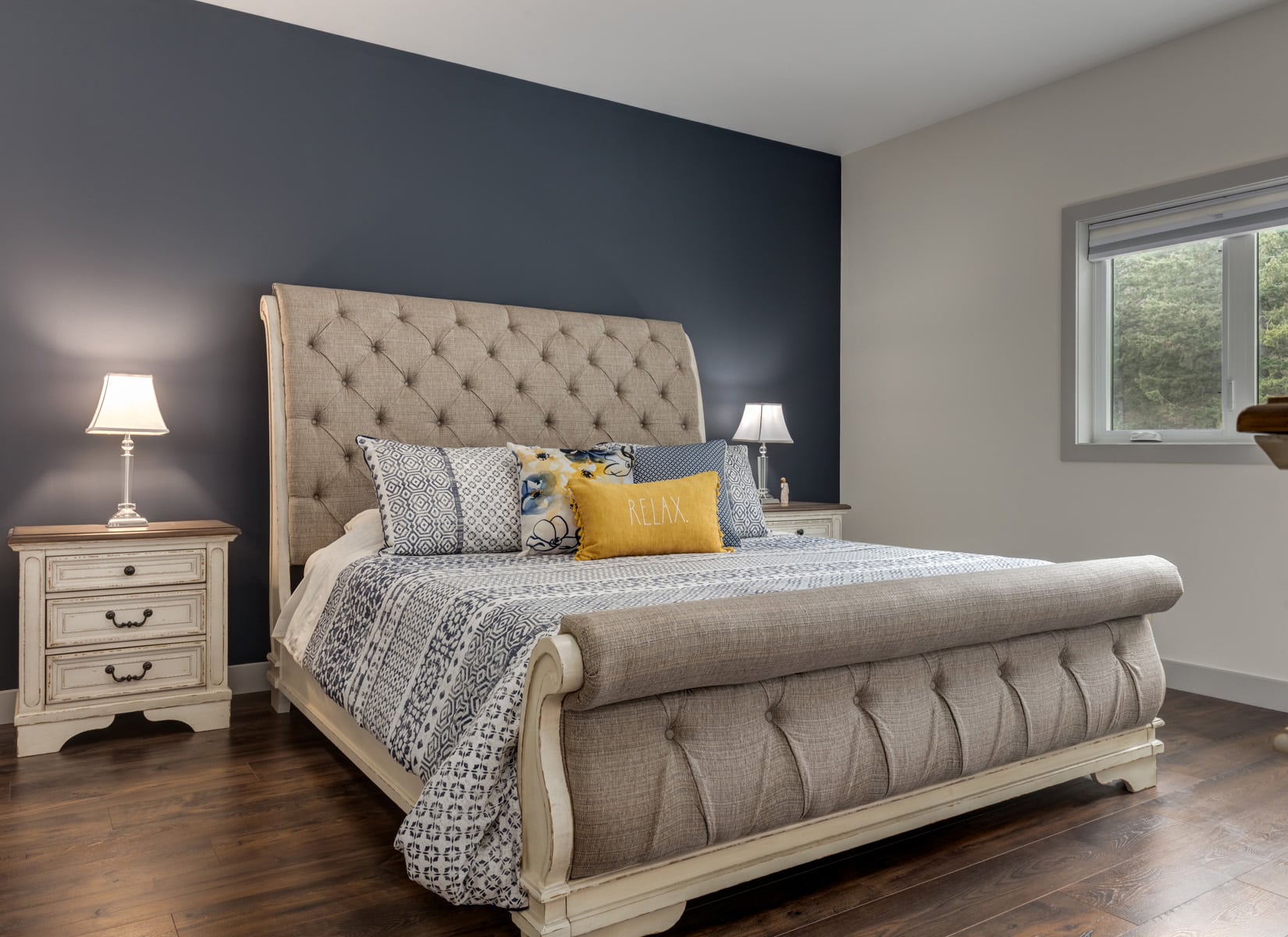 A cozy bedroom featuring blue walls and a neatly made white bed, creating a calm and inviting atmosphere.